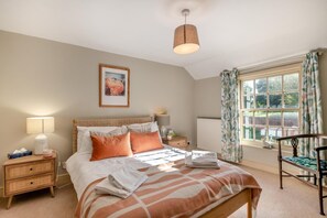 A bedroom with a bed, bedside tables, a lamp, a radiator, a window with curtains, and a picture on the wall. - 3 Bed in Wangford (oc-c18609) (Wangford)