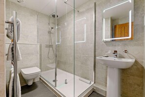 Une salle de bain moderne avec une douche à parois de verre, des toilettes blanches et un lavabo sur colonne.