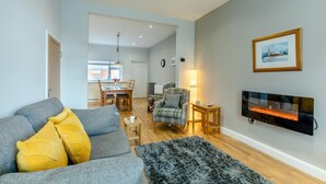A modern living room with a grey sofa, a plaid armchair, and a fireplace. - 2 Bed in Amble (oc-b28345) (Amble)