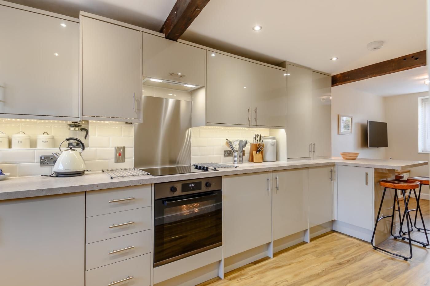 A modern kitchen with stainless steel appliances, white cabinetry, and a wooden floor.