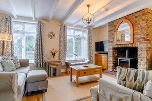 A cozy living room with a fireplace, a sofa, a coffee table, and a television. - 4 Bed in Sheringham (oc-m28357) (Sheringham)