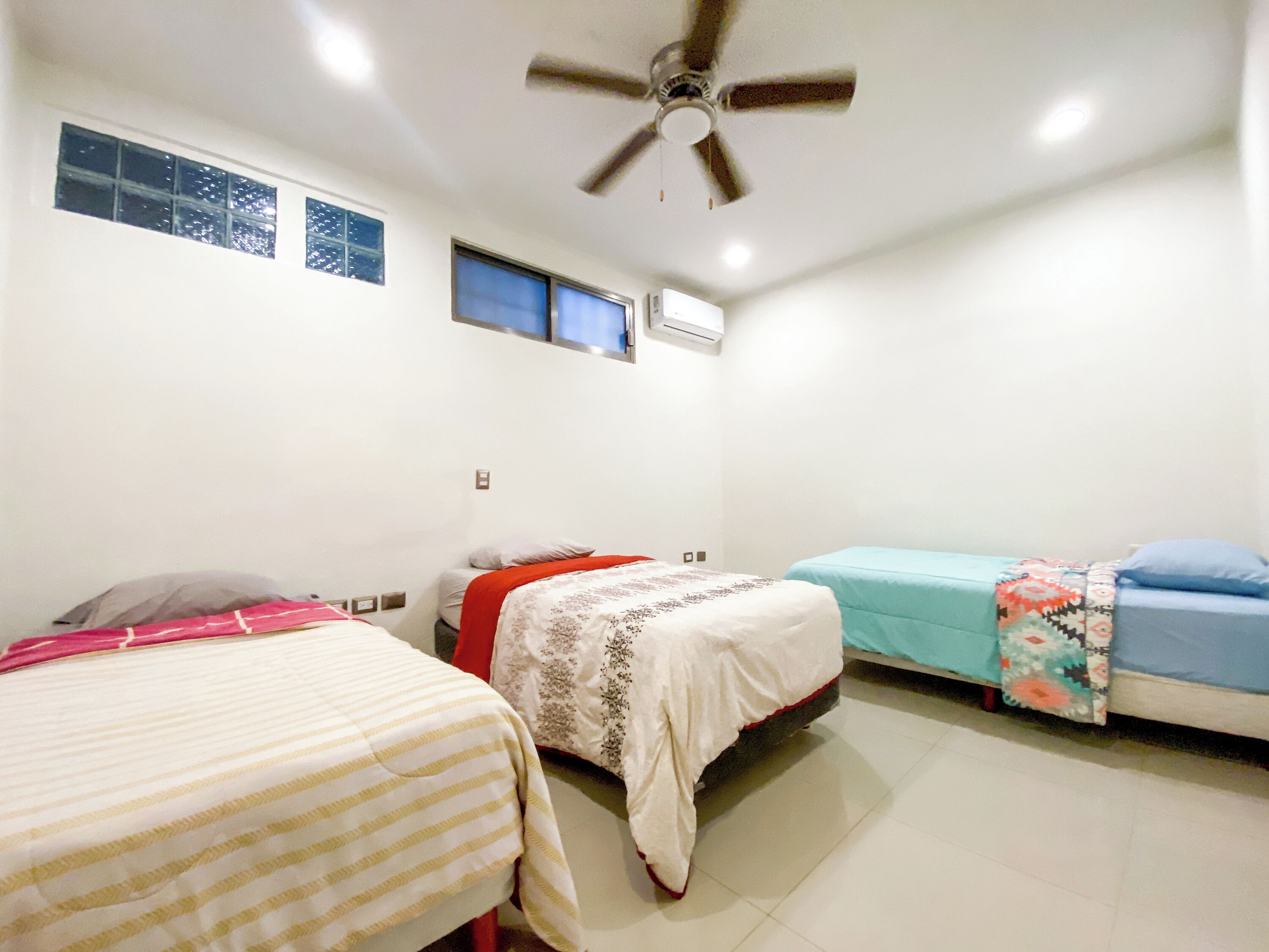 A room with two beds, a ceiling fan, and an air conditioning unit.