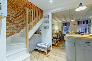 A kitchen with a wooden staircase, grey cabinets, and a dining area with a view of the outside. - 3 Bed in Whitby (oc-s28346) (Whitby)