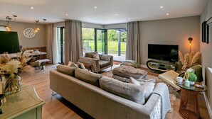 Ein modernes Wohnzimmer mit einer großen Couch, einem Fernseher und einem Essbereich mit Tisch und Stühlen.