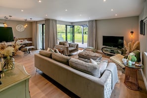 A modern living room with a large sofa, a television, and a dining area with a table and chairs.