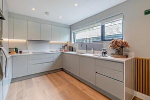 A modern kitchen with a built-in oven, a sink, and a window above the countertop.