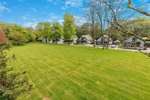 A well-maintained grassy area with modern houses, a clear sky, and trees.