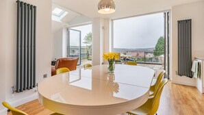 A modern dining area with a round table, yellow chairs, and a vase of flowers. - 4 Bed in Killay (oc-c28372) (Killay)