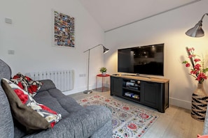 A modern living room with a grey sofa, a flat-screen TV, a floor lamp, and a decorative rug. - 1 Bed in Truro (oc-p28365) (Blackwater)