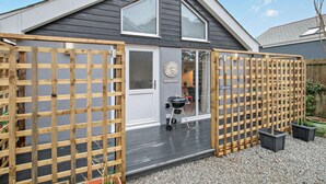 Et hus med mørkegrå facade, hvid dør og træterrasse.