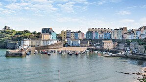 A coastal town with colorful buildings, a harbor with boats, and a stone fortification. - 2 Bed in Tenby (oc-f28369) (Tenby)