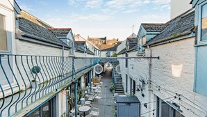 A narrow alleyway with buildings on either side, outdoor seating, and a metal railing. - 2 Bed in Tenby (oc-f28369) (Tenby)