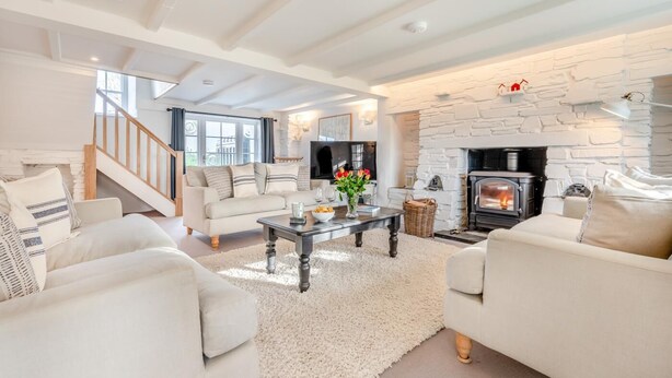 Ein modernes Wohnzimmer mit Kamin, weißen Sofas, einem Couchtisch und einer Treppe.