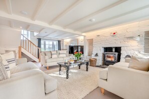 Ein modernes Wohnzimmer mit Kamin, weißen Sofas, einem Couchtisch und einer Treppe.