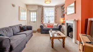 Ein gemütliches Wohnzimmer mit Kamin, zwei Sofas, einem Couchtisch und einem Bücherregal.