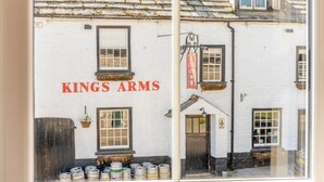 Ein Gebäude mit dem Schild „KINGS ARMS“ und einem Fenster, das verschiedene Artikel zeigt.