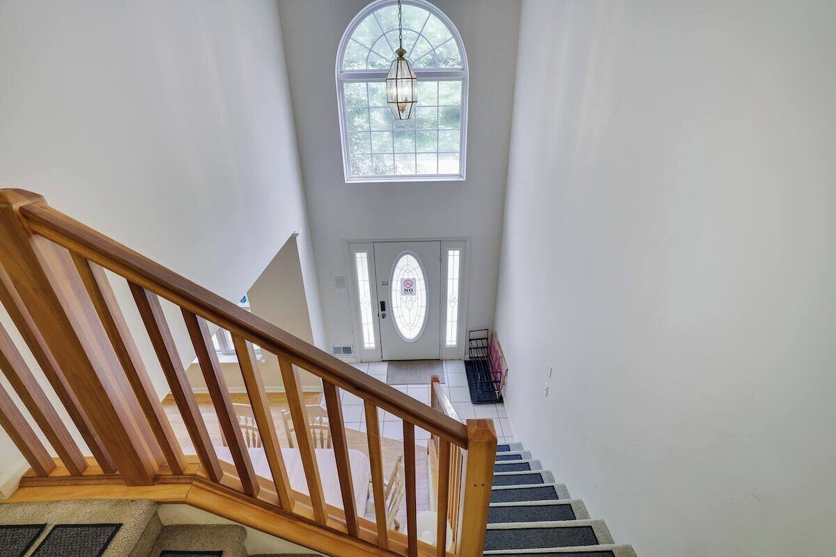 A staircase leading to a door with a '101' sign, a large arched window, and a hanging light fixture.