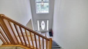 A staircase leading to a door with a '101' sign, a large arched window, and a hanging light fixture. - Backyard lake-Boat– Kayaks • Firepit • Game room• pool access • Pet-friendly (Coolbaugh Township)