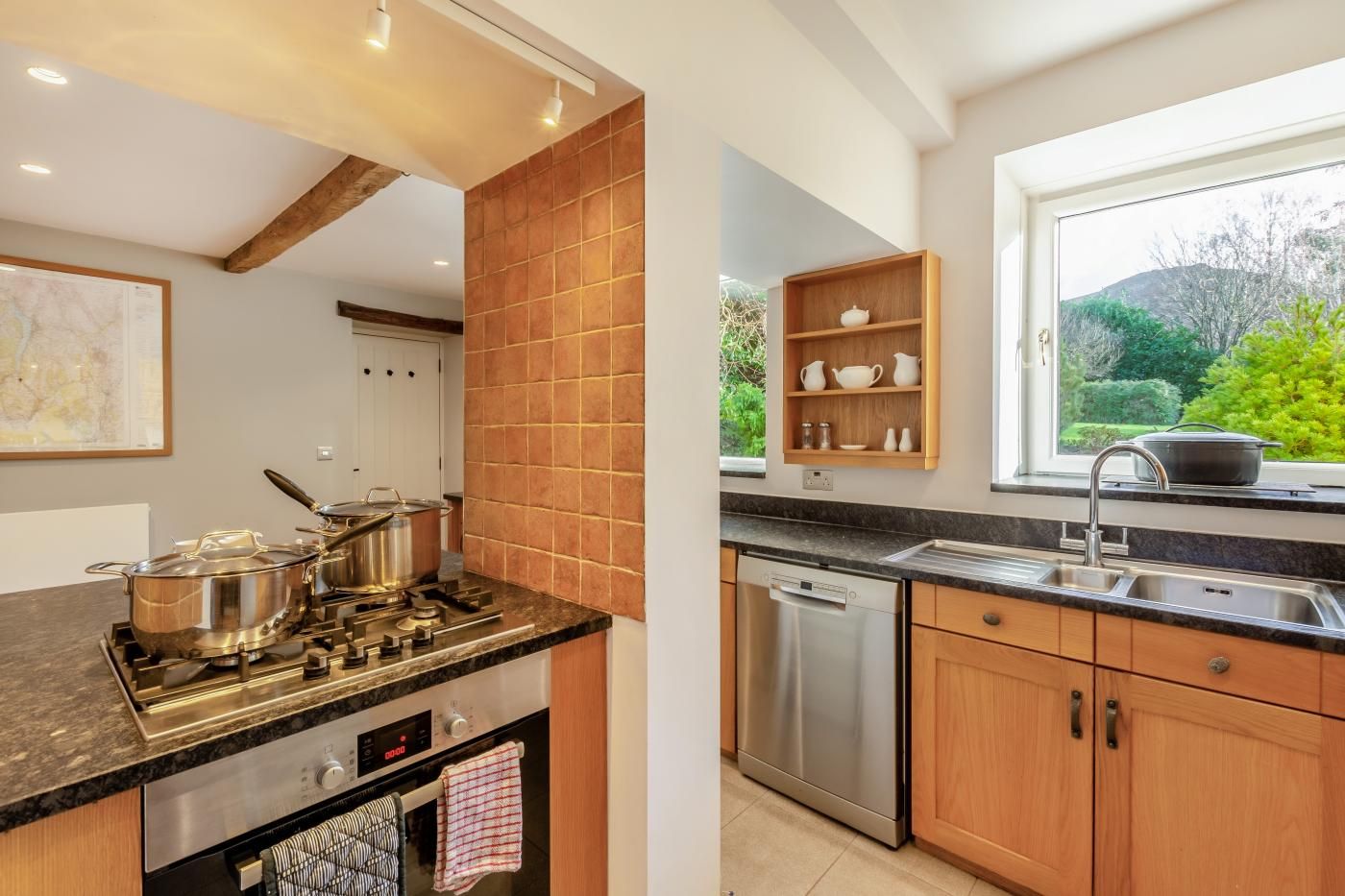 A modern kitchen with a gas stove, oven, dishwasher, and wooden cabinets.