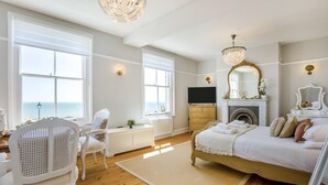 Un dormitorio con cama, televisor, chimenea y ventanas amplias.