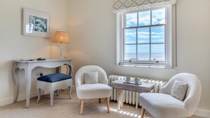 Une pièce comprenant un bureau, deux chaises, un radiateur et une fenêtre donnant sur un paysage agréable.