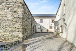 A narrow alleyway with stone walls, a paved path, and buildings with windows and doors. - 2 Bed in Newby Bridge (oc-o28384) (Newby Bridge)