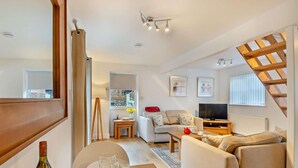 A modern living room with a sofa, TV, and dining area with a bottle and glasses. - 2 Bed in Bodham (oc-m15008) (Bodham)