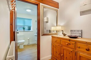 A bathroom with a wooden cabinet, a mirror, a sign reading 'MULBERRY HOUSE,' a lamp, and a bird decoration. - 2 Bed in Bodham (oc-m15008) (Bodham)