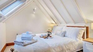 A bedroom with a sloped ceiling, a bed with white linens, a bedside table, and a nightstand. - 2 Bed in Bodham (oc-m15008) (Bodham)