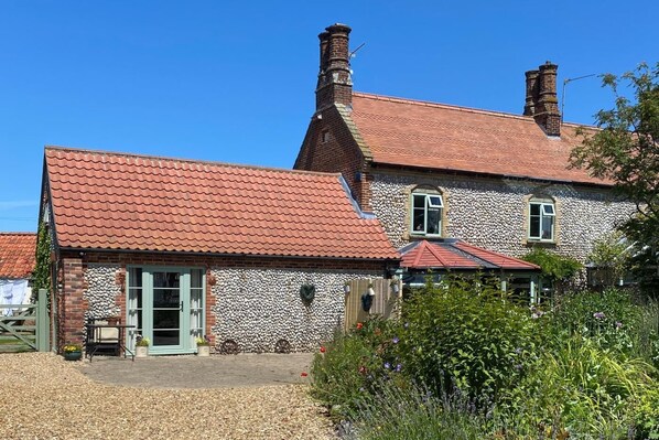 A two-story house with a red-tiled roof, stone exterior, and a front garden. - 2 Bed in Bodham (oc-m15008) (Bodham)
