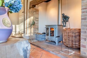 A rustic interior with a wood-burning stove, a stone fireplace, and a wicker basket. - 3 Bed in Monk Soham (oc-h28366) (Monk Soham)