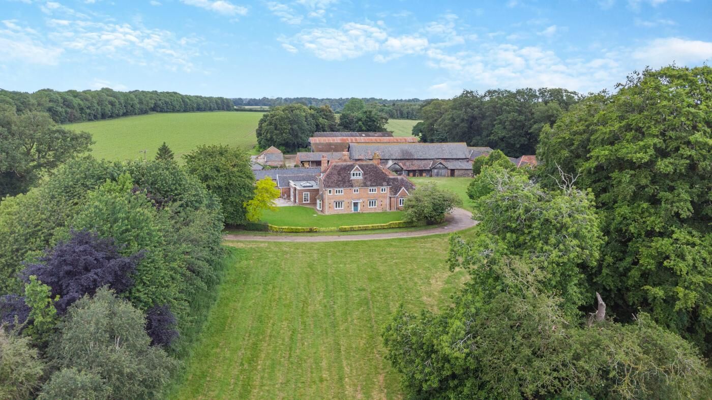 A large estate with multiple buildings, surrounded by lush greenery and open fields.