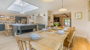 Une cuisine moderne dotée d’un îlot central, d’un coin repas avec une table et des chaises en bois, et offrant une vue sur l’extérieur.