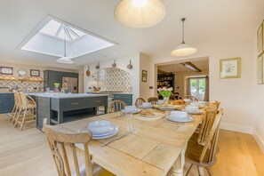 Une cuisine moderne dotée d’un îlot central, d’un coin repas avec une table et des chaises en bois, et offrant une vue sur l’extérieur.