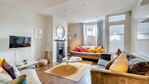 A modern living room with a flat-screen TV, a fireplace, a sofa set, and a coffee table. - 2 Bed in Whitstable (oc-f28381) (Whitstable)