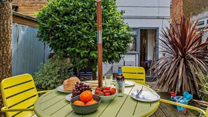 A round table with a green tablecloth, two yellow chairs, a bowl of fruit, a bottle, and a glass. - 2 Bed in Whitstable (oc-f28381) (Whitstable)