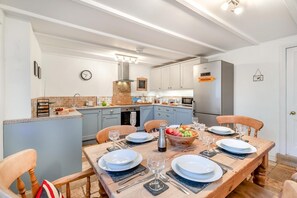 A modern kitchen with a dining area set for six. - 3 Bed in Pendeen (oc-t22674) (Pendeen)