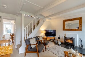 Ein Wohnzimmer mit Treppe, Fernseher, Kamin und Essbereich.