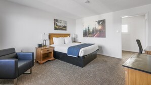 A bedroom with a bed, a desk, a chair, and two paintings on the wall.