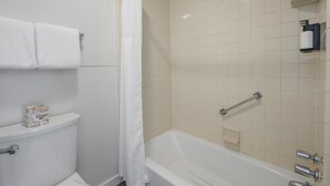 A bathroom with a toilet, a bathtub, a shower curtain, and a towel rack.