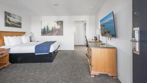 A hotel room with a bed, a desk, a dresser, and a TV.