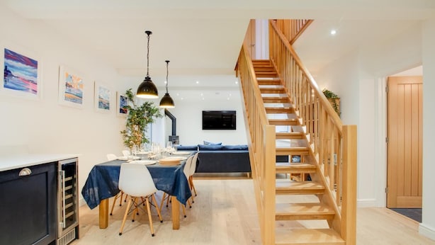 Et moderne interiør med spiseområde, trætrappe og opholdsstue.