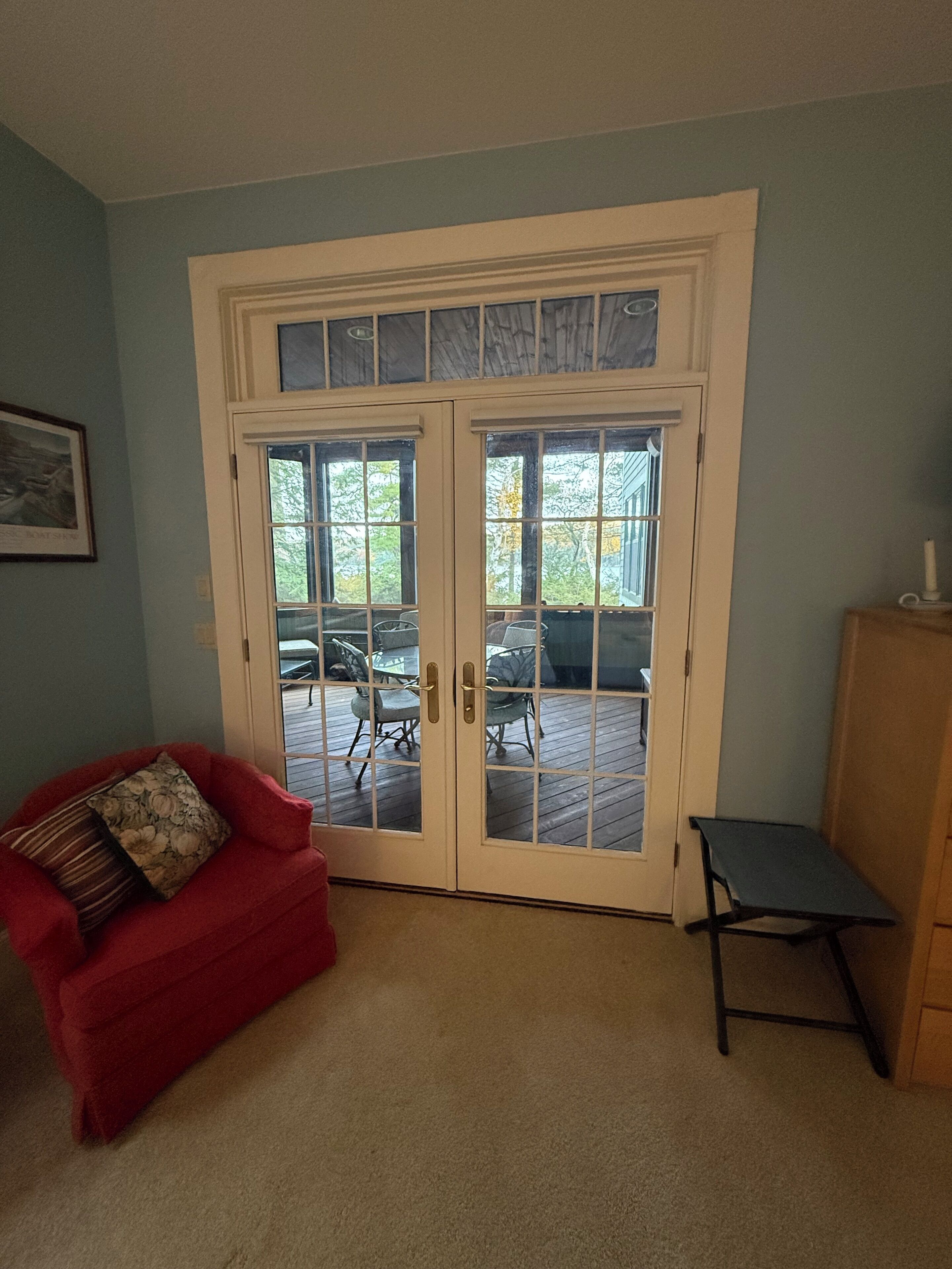 A room with a red sofa, a small table, and a sliding glass door leading to an outdoor deck.