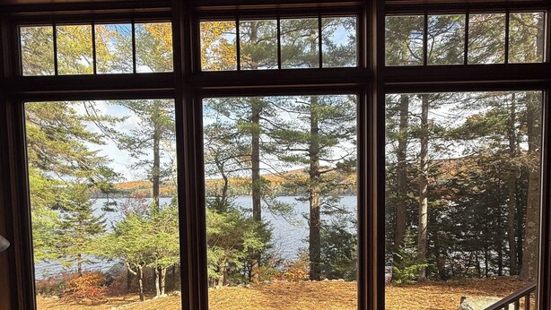 A room with a large window overlooking a forested area with a lake.