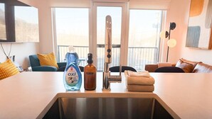 A modern kitchen with a stainless steel sink, a bottle of dish soap, and a towel stack. - The Cache Contemporary DT Condo (Golden)
