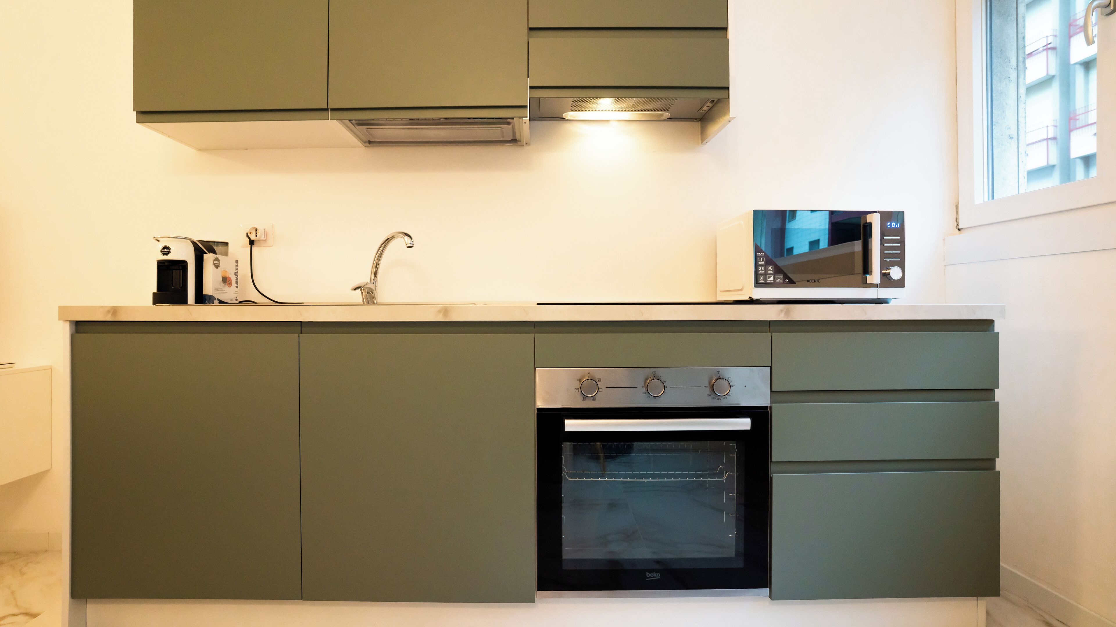 A compact kitchen with a built-in oven, a microwave, and a sink.