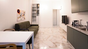 Moderni keittiö, jossa on marmorilattia, sohva, ruokapöytä ja televisio.