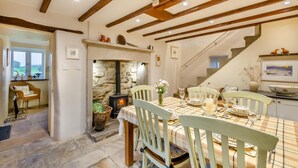 A dining area with a table set for four, a stone fireplace, and a staircase leading upstairs. - 3 Bed in Gunnerside (oc-t28301) (Satron)