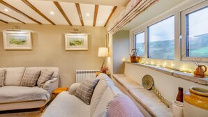 A cozy room with a sofa, a radiator, a window with a view, and a lamp. - 3 Bed in Gunnerside (oc-t28301) (Satron)