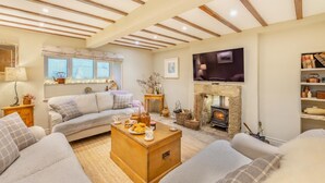 A cozy living room with a sofa, a wooden coffee table, a fireplace, and a television mounted on the wall. - 3 Bed in Gunnerside (oc-t28301) (Satron)